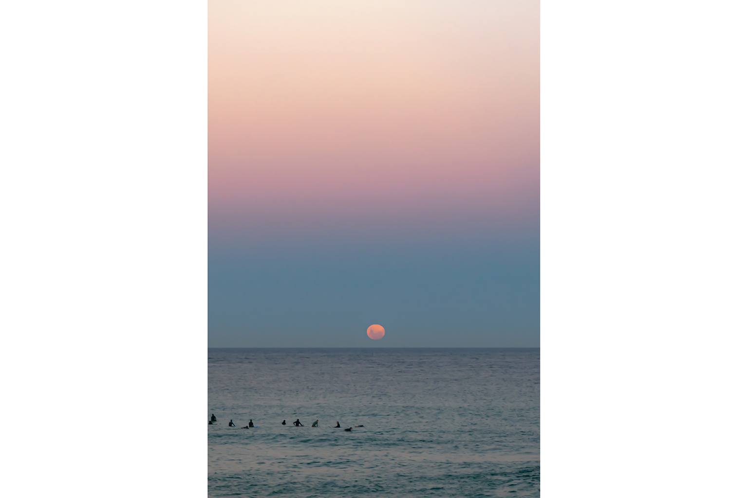 Moon rising above surfers